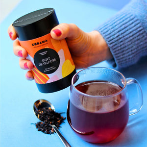 Gant de Velours Bio – Thé noir, Fèves de Cacao, Chicorée – Kodama Paris - Main qui  tient la boite de gant de velours - Tasse avec élixir et vrac dans une cuilliere 